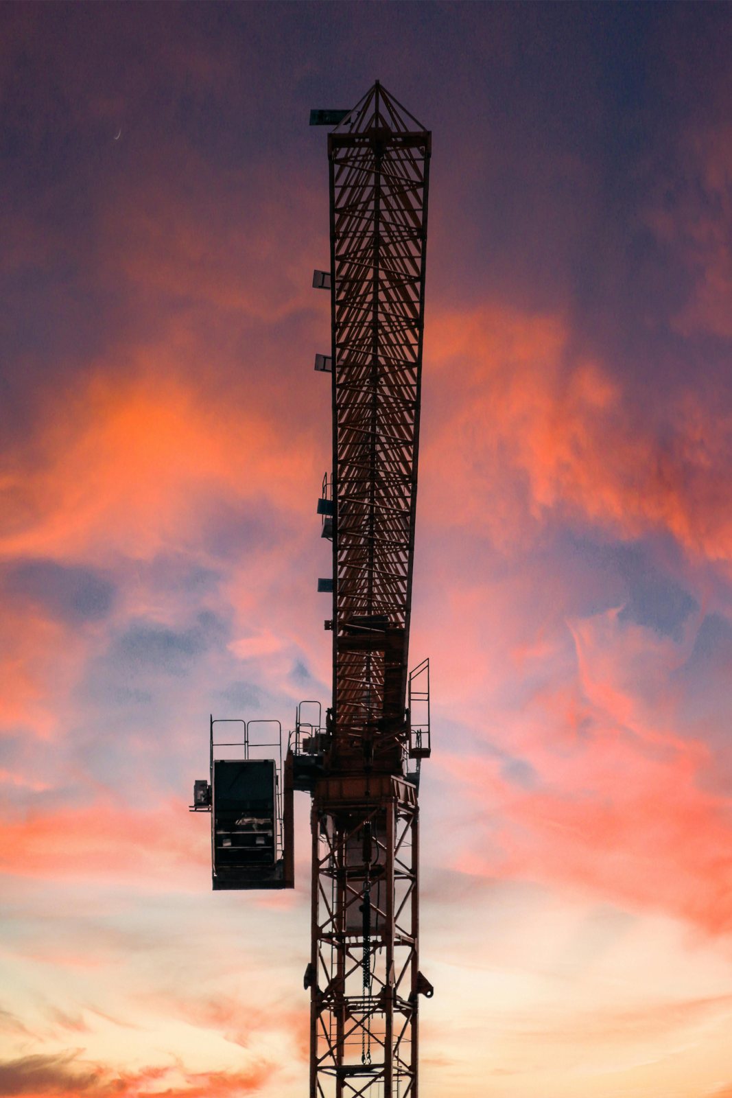 Une grue de chantier sous un ciel orange et violet